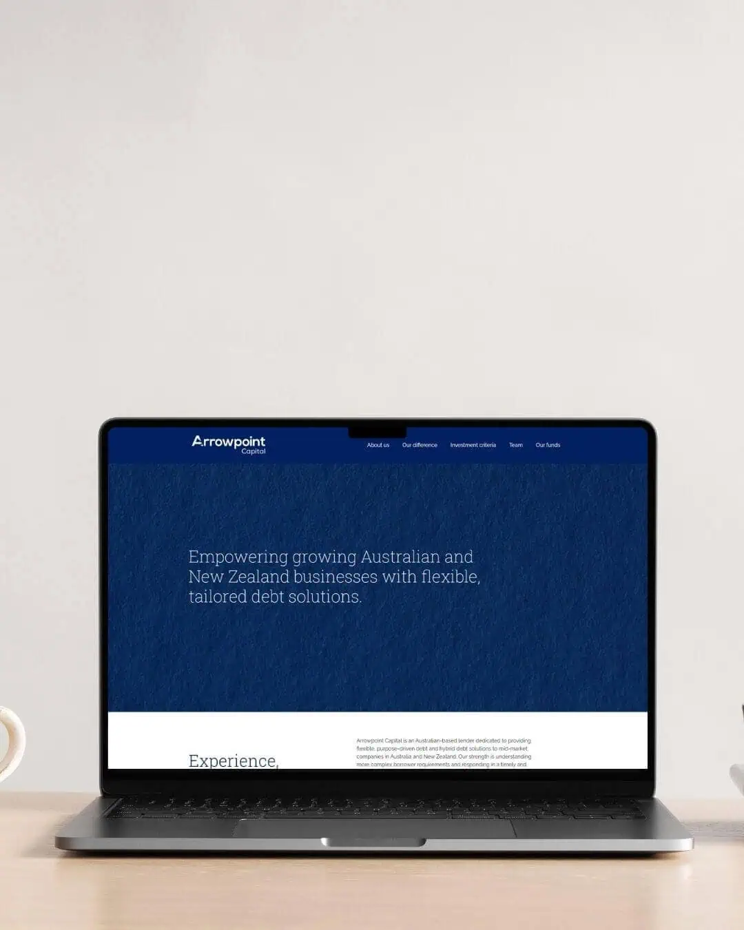 A laptop on a desk displays a website for Arrowpoint Capital, featuring text about tailored debt solutions for Australian and New Zealand businesses.