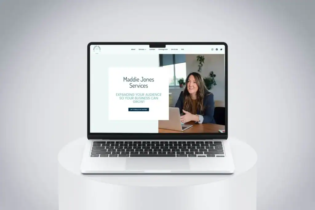A laptop on a white stand displays a website for Maddie Jones Services, featuring a woman smiling at a desk and text about expanding business audiences.