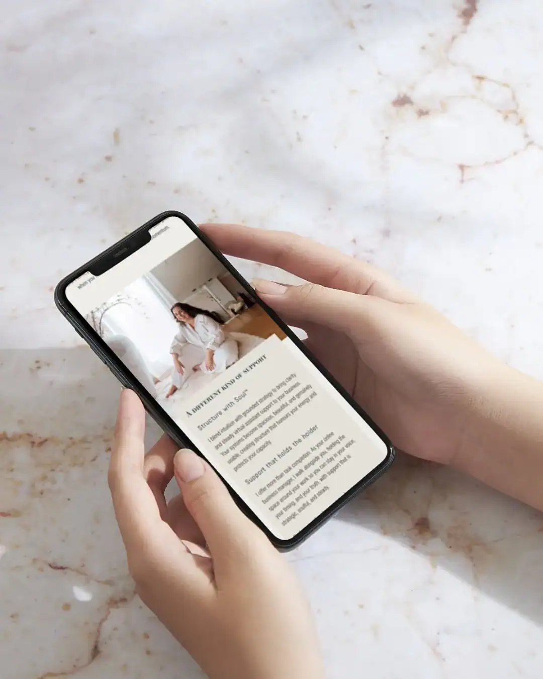 A person holds a mobile displaying an article with a woman sitting indoors and text below her photo.
