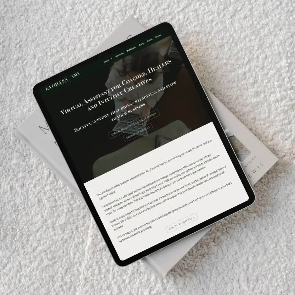 Tablet displaying a website rests on two stacked books on a white textured surface, viewed from above.